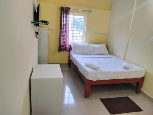 a small room with two beds and a window at ISIRI Rooms in Mysore