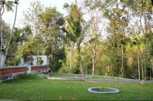 a park with green grass and palm trees at Neerbhoomi in Kollam