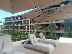 two chairs and an umbrella on a patio with a building at Wing Samui Condo 102 in Nathon Bay