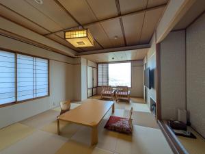 a living room with a table and a tv at Nakamatsuya Ryokan in Ueda