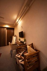 a room with a couch and a chair and a television at Midnight Atelier in Greater Noida