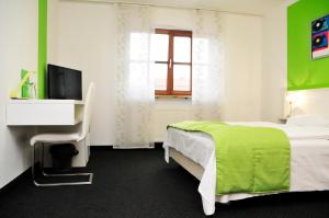 a bedroom with a green and white bed and a television at Hotel zum Brunnen in Friedberg