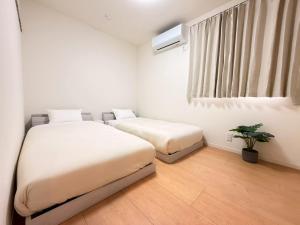 a bedroom with two beds and a potted plant at Franmare in Okayama