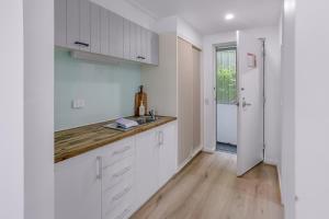 a kitchen with white cabinets and a wooden floor at Bay View Style in Lorne
