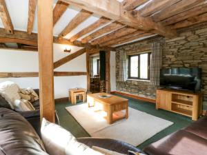 a living room with a couch and a tv at Redstart Cottage in Leominster