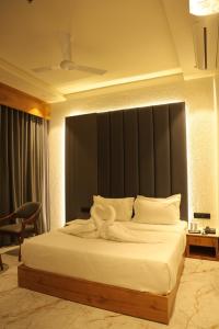 a bedroom with a large bed with white sheets at Hotel Barai Palace in Dwarka