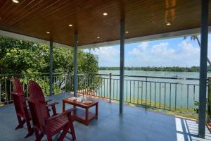 a porch with chairs and a table and a view of the water at Akanta Cherai Beach Resort in Cochin +6 photos