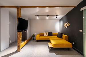 a living room with a yellow couch and a tv at ARI Central Location in Arad