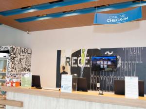 a store counter with a television on a wall at ibis budget Manhuaçu in Manhuaçu +84 photos