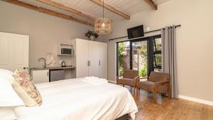 a bedroom with a white bed and two chairs at The Wellington Residence in George