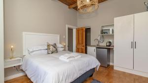 a bedroom with a large white bed and a kitchen at The Wellington Residence in George +21 photos