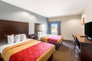 a hotel room with two beds and a desk at Econo Lodge Baton Rouge University Area in Baton Rouge