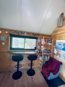 a tiny house with two bar stools and a window at Ecologic glamping in Estevais