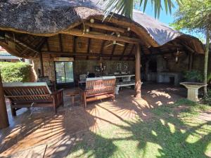 a patio with two benches and a large umbrella at Lala Bela Guest House in Bela-Bela +7 photos