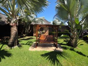 a swing in a yard with palm trees at Lala Bela Guest House in Bela-Bela