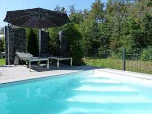 a swimming pool with a table and an umbrella at Ferienwohnung Seenlandwinkel in Wackersdorf