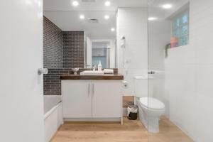 a white bathroom with a sink and a toilet at Bay View - Palm Springs in Lorne +11 photos