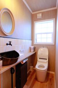 a bathroom with a sink and a toilet and a mirror at KOGUMA AKIRUNO villa in Akiruno