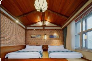 two beds in a room with a brick wall at Hidden paradise homestay in Rongli