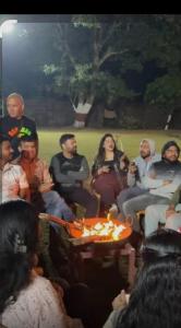 a group of people sitting around a table with a fire at Hidden paradise homestay in Rongli