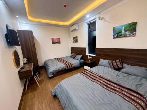 a hotel room with two beds and a tv at XƠ ĐĂNG homestay in Kon Plong