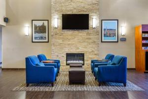 a waiting room with blue chairs and a fireplace at Comfort Suites Dover University Area in Dover