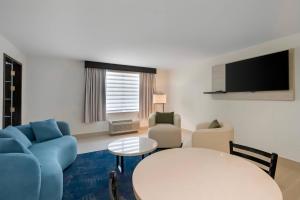 a living room with a table and chairs and a tv at Blue A Modern Hotel, an Ascend Collection Hotel in West Springfield