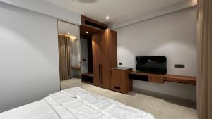 a bedroom with a bed and a flat screen tv at Cloud Nine Hotel - Kuthuparamba in Kūttuparamba