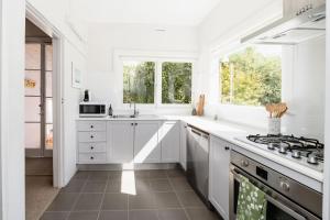a white kitchen with a stove and a window at Maison del Mar in Hobart