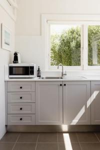 a white kitchen with a microwave and a window at Maison del Mar in Hobart +32 photos