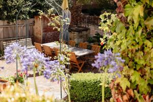 a garden with a table and chairs and purple flowers at Maison del Mar in Hobart
