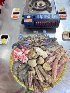 a plate of seafood and vegetables on a table with aeper at Hương Dịu Hotel đảo Quan Lạn in Quan Lạn