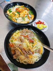 two black bowls of food with noodles and meat at Hương Dịu Hotel đảo Quan Lạn in Quan Lạn