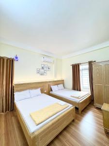 two beds in a room with wooden floors at Hương Dịu Hotel đảo Quan Lạn in Quan Lạn