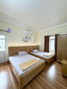 two beds in a room with wooden floors at Hương Dịu Hotel đảo Quan Lạn in Quan Lạn