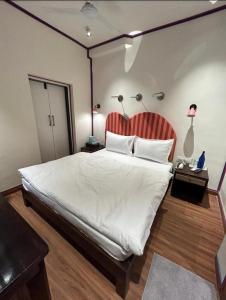 a bedroom with a large white bed with a red headboard at Boho Villa Mount Abu in Mount Ābu +12 photos
