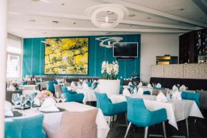 a dining room with white tables and blue chairs at DämeritzSeehotel in Berlin