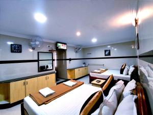 a room with two beds and a flat screen tv at Hotel GVS Residency in Yercaud
