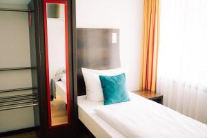 a room with a bed with a blue pillow on it at DämeritzSeehotel in Berlin +17 photos