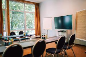 a conference room with a table and chairs and a flat screen tv at DämeritzSeehotel in Berlin