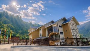 a house with a balcony with mountains in the background at Yashshree Dewathang Resort in Lachung