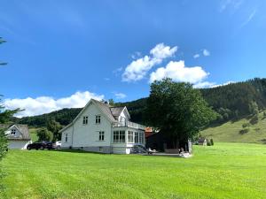 a large white house on a grassy field at Lake House in Vossevangen
