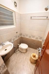 a bathroom with a toilet and a sink at Manjusri Paradise in Bangalore