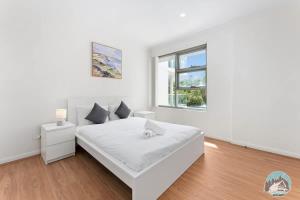 a white bedroom with a bed and a window at Epping 2BR House with Parking in Epping