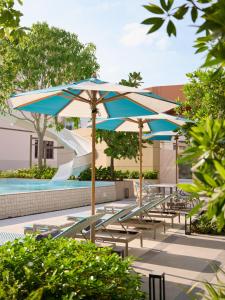 a group of tables and umbrellas next to a pool at Marni Pattaya in Pattaya South