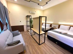 a hotel room with two beds and a couch at Berlian Abadi Hotel by Sinergi in Banyuwangi