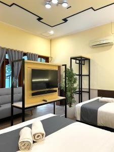 a bedroom with two beds and a flat screen tv at Berlian Abadi Hotel by Sinergi in Banyuwangi