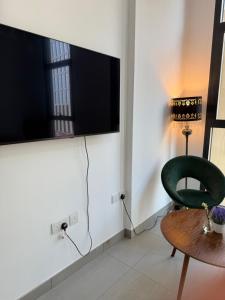 a living room with a green chair and a flat screen tv at Modern studio with pool and fiber connection in Sharjah +2 photos