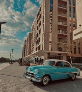 an old blue car parked in front of a building at Modern studio with pool and fiber connection in Sharjah