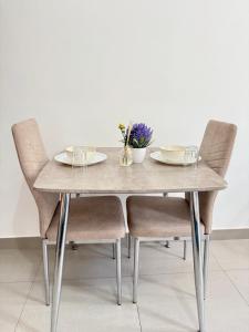 a dining table with two chairs with plates and flowers on it at Modern studio with pool and fiber connection in Sharjah